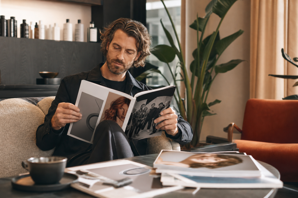 Friseur liest eine moderne Fachzeitschrift in einem Salon.