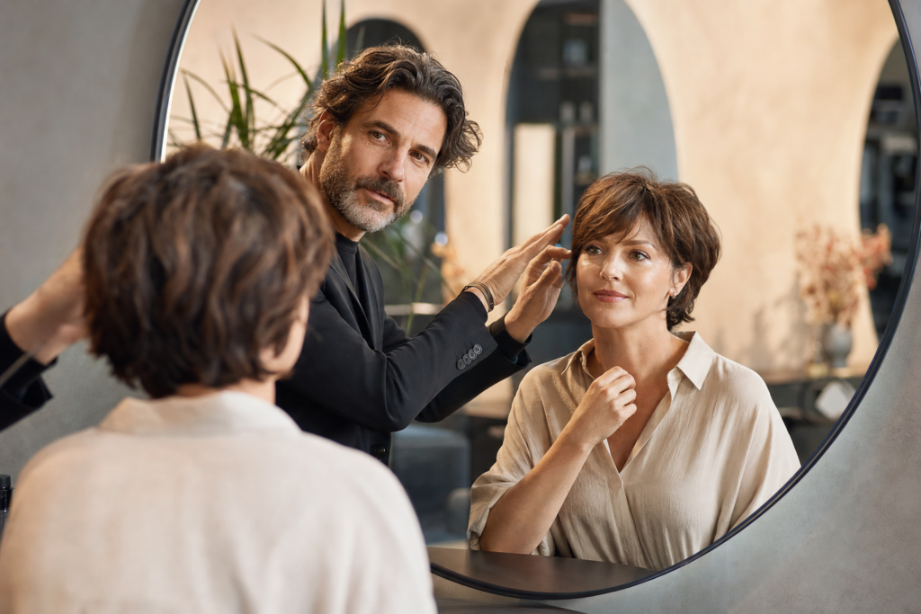 Friseur berät eine Kundin am Spiegel zu einer typgerechten Frisur.